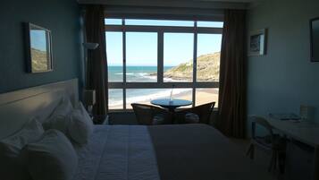 A hotel room with a bed, a small round table, and a view of the beach.