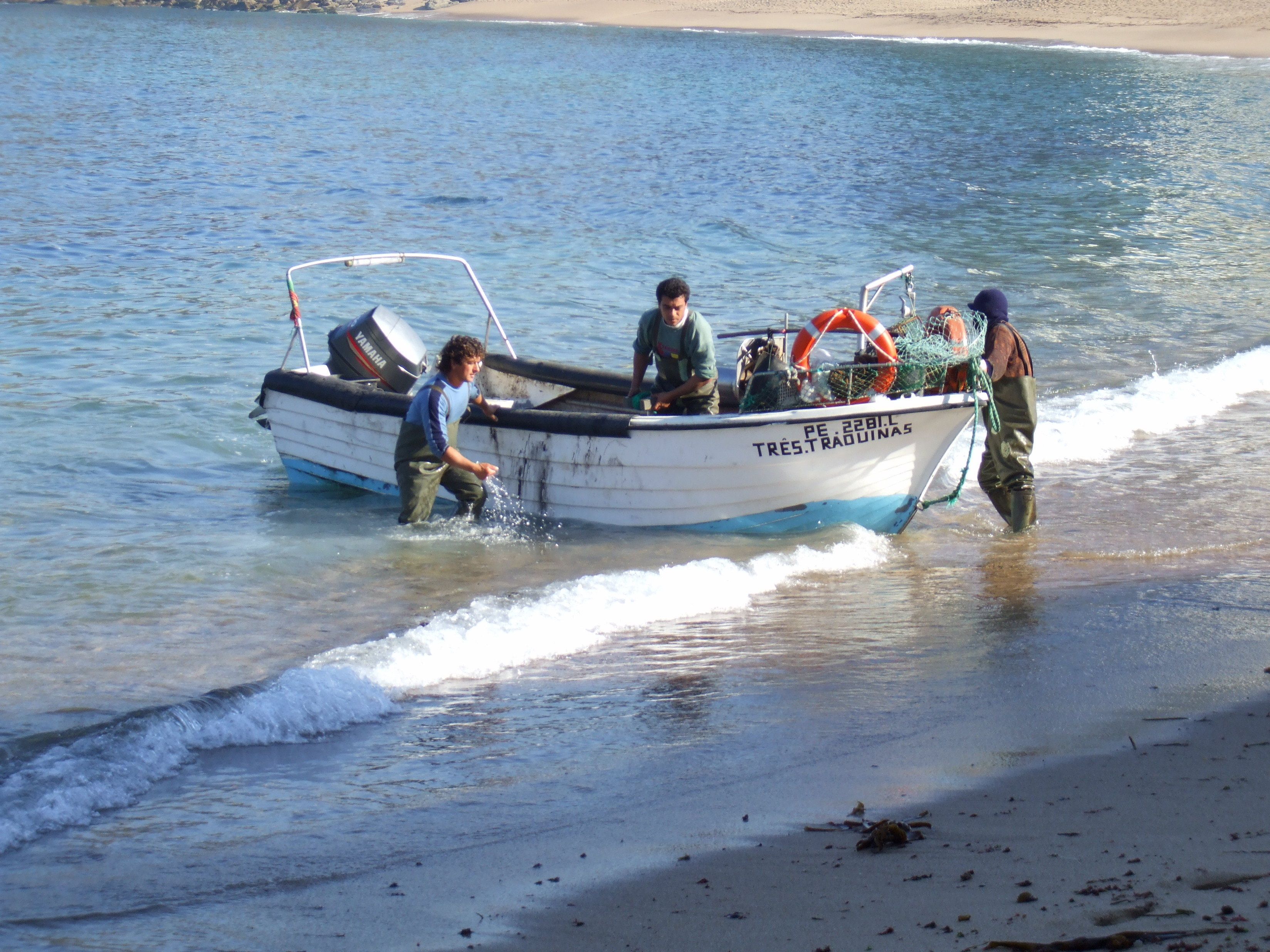 A boat with people on it, moving towards the shore.