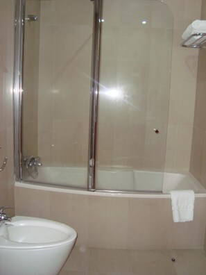A bathroom with a glass-enclosed shower, a bathtub, and a sink. - Hotel Albergaria Borges (Chaves)