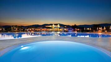 Una piscina grande al aire libre con un área de patio y un edificio al fondo.