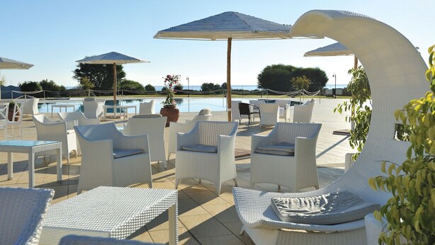 A poolside area with white wicker furniture and umbrellas.