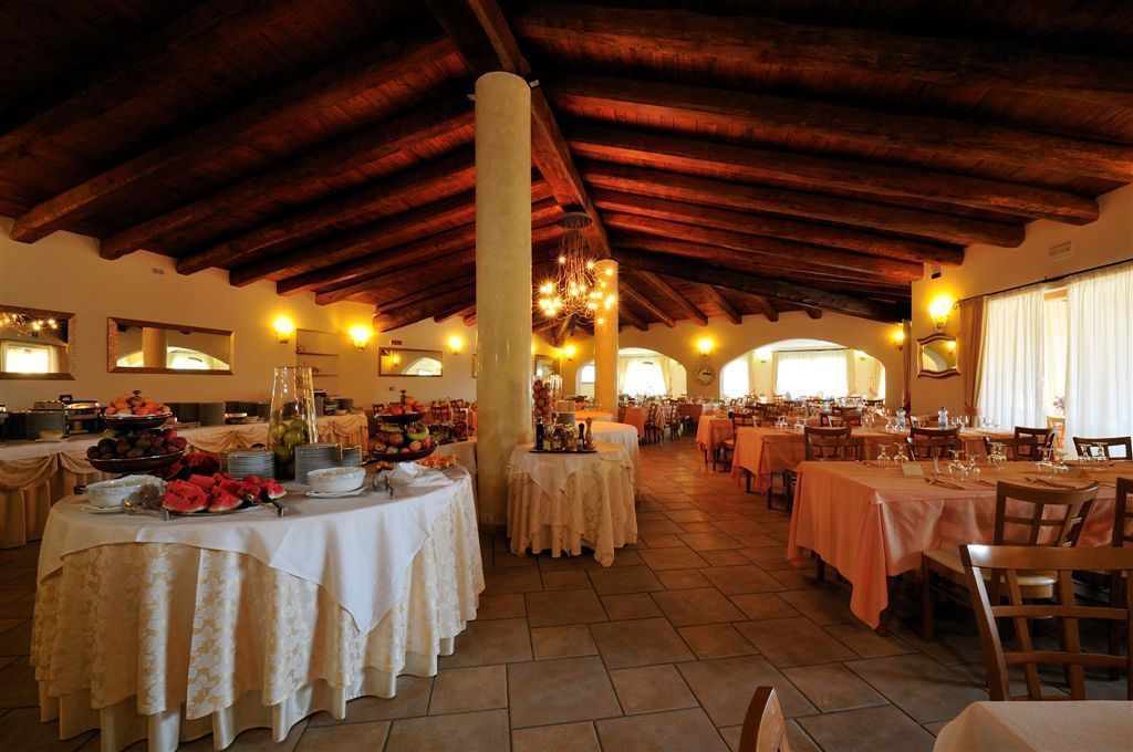 Un'ampia sala da pranzo con alti soffitti in legno e numerosi tavoli apparecchiati per un pasto.