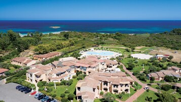 Un resort con piscina central, varias villas y vista al mar.