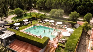 A rooftop pool area with multiple swimming pools, lounge chairs, and umbrellas.