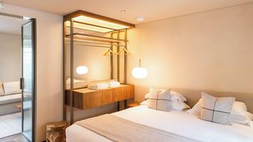 Ein modernes Hotelzimmer mit einem großen Bett, einem Nachttisch aus Holz, einem Spiegel und einer Pendelleuchte.