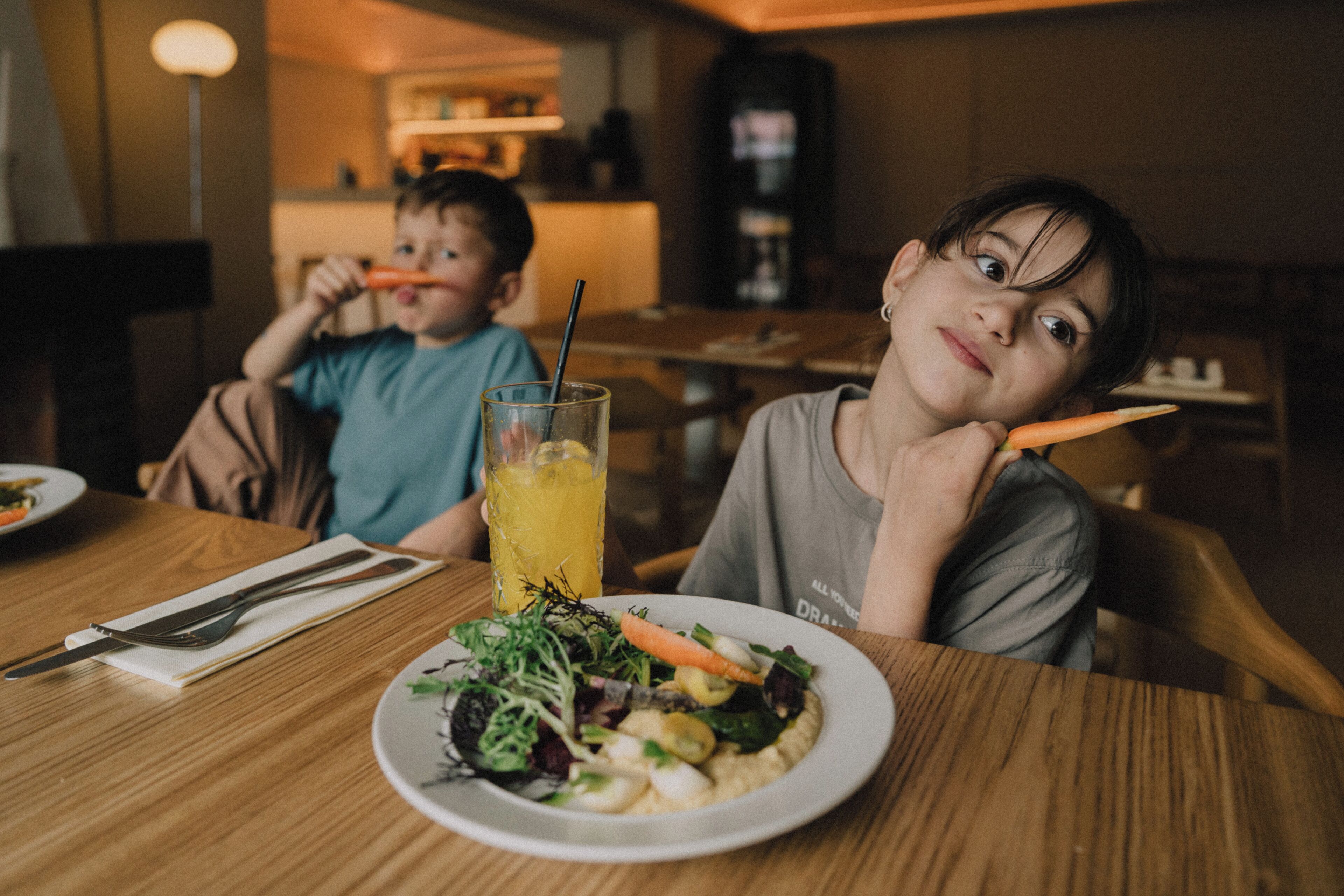 Une table à manger avec une assiette de nourriture, un verre de jus de fruits et des couverts.
