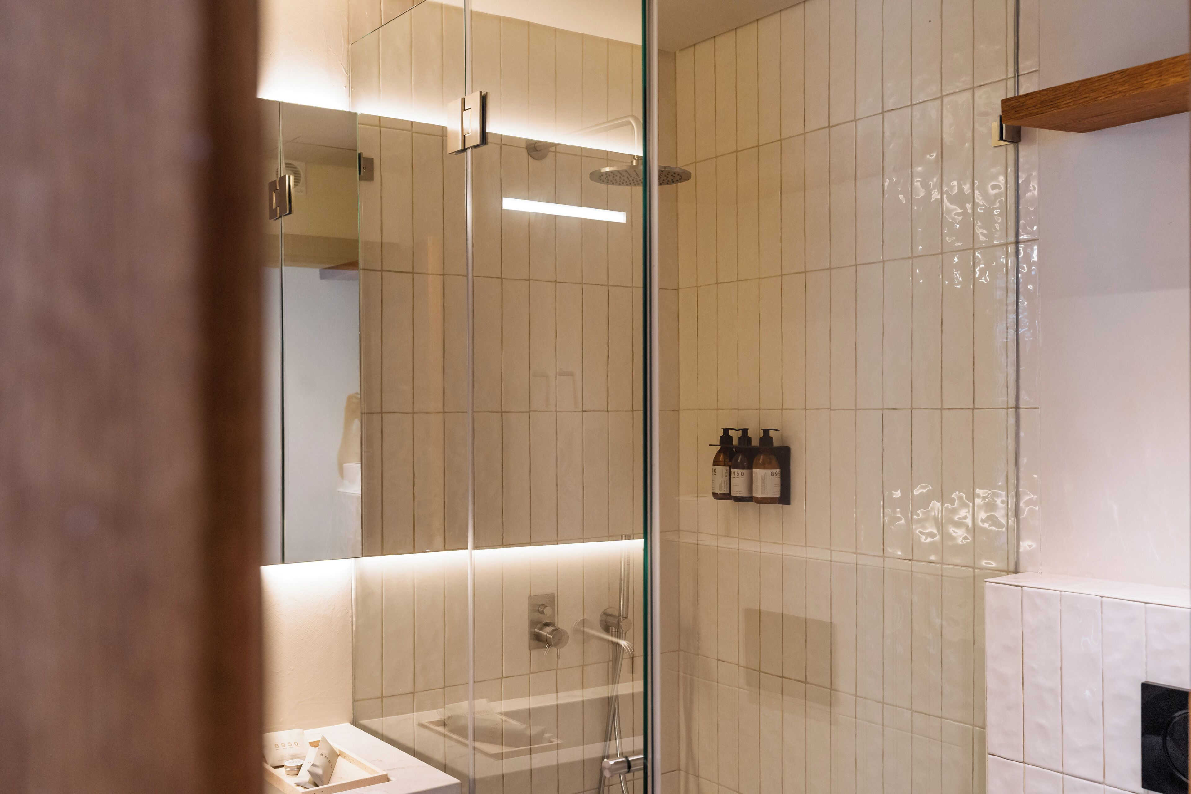 A modern bathroom with a glass shower enclosure, a white sink, and a mirror.