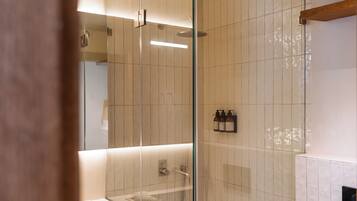 A modern bathroom with a glass shower enclosure, a white sink, and a mirror.