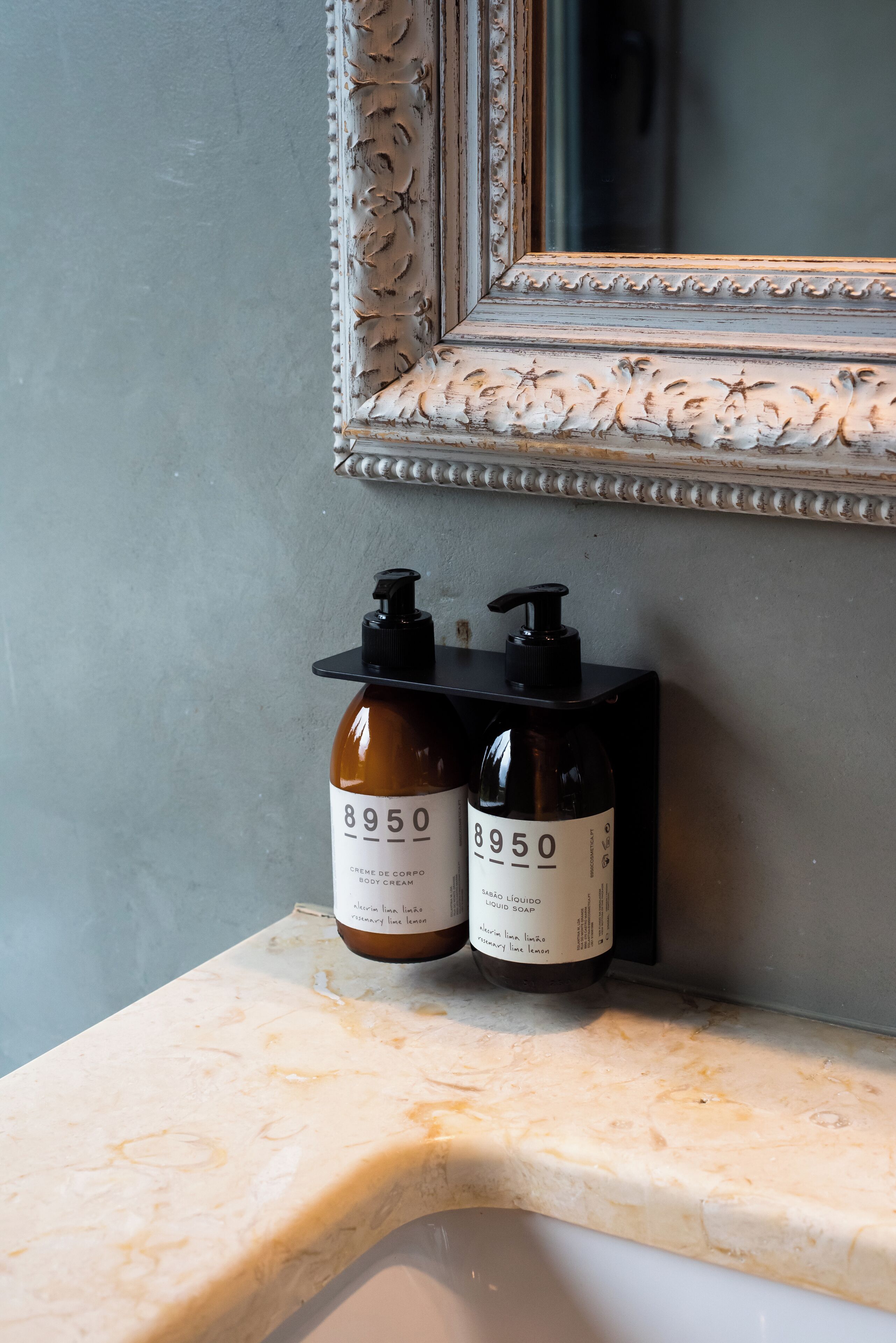 Dos botellas de crema corporal sobre un mostrador de baño con un espejo arriba.