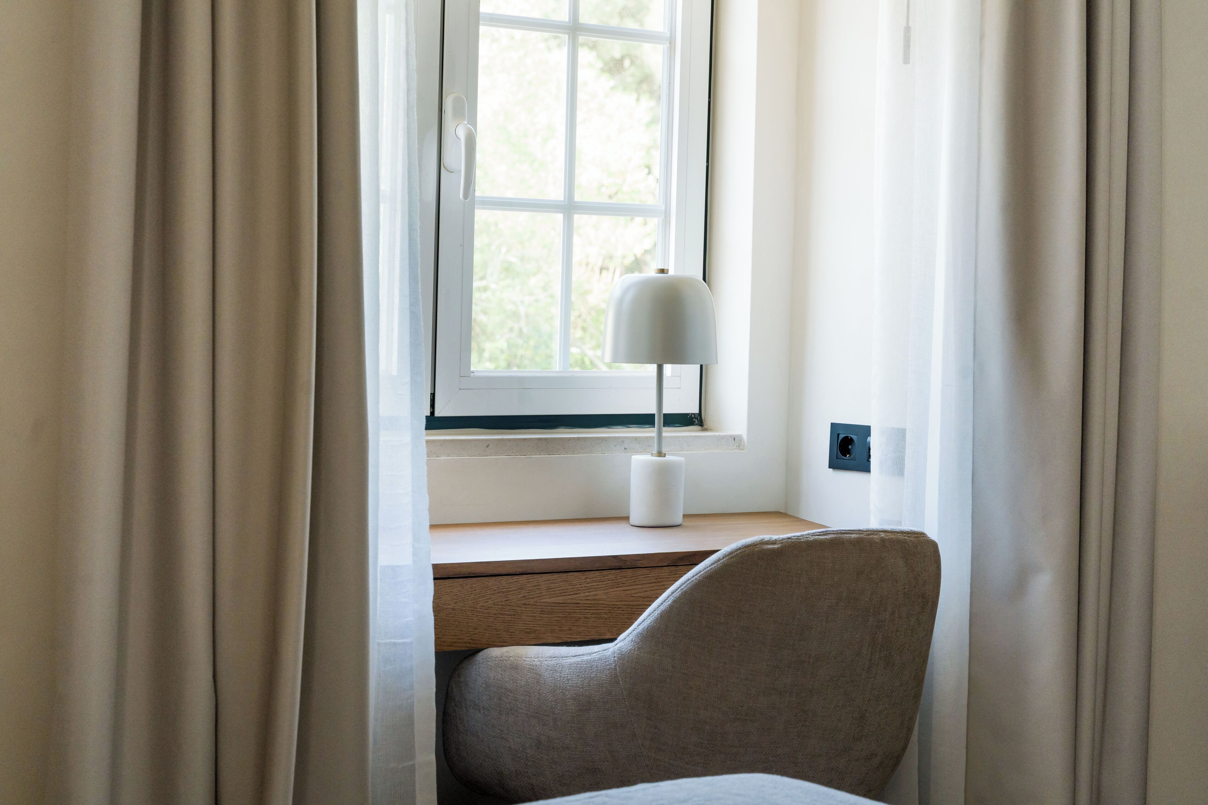 A room with a window, a desk, a chair, and a lamp.