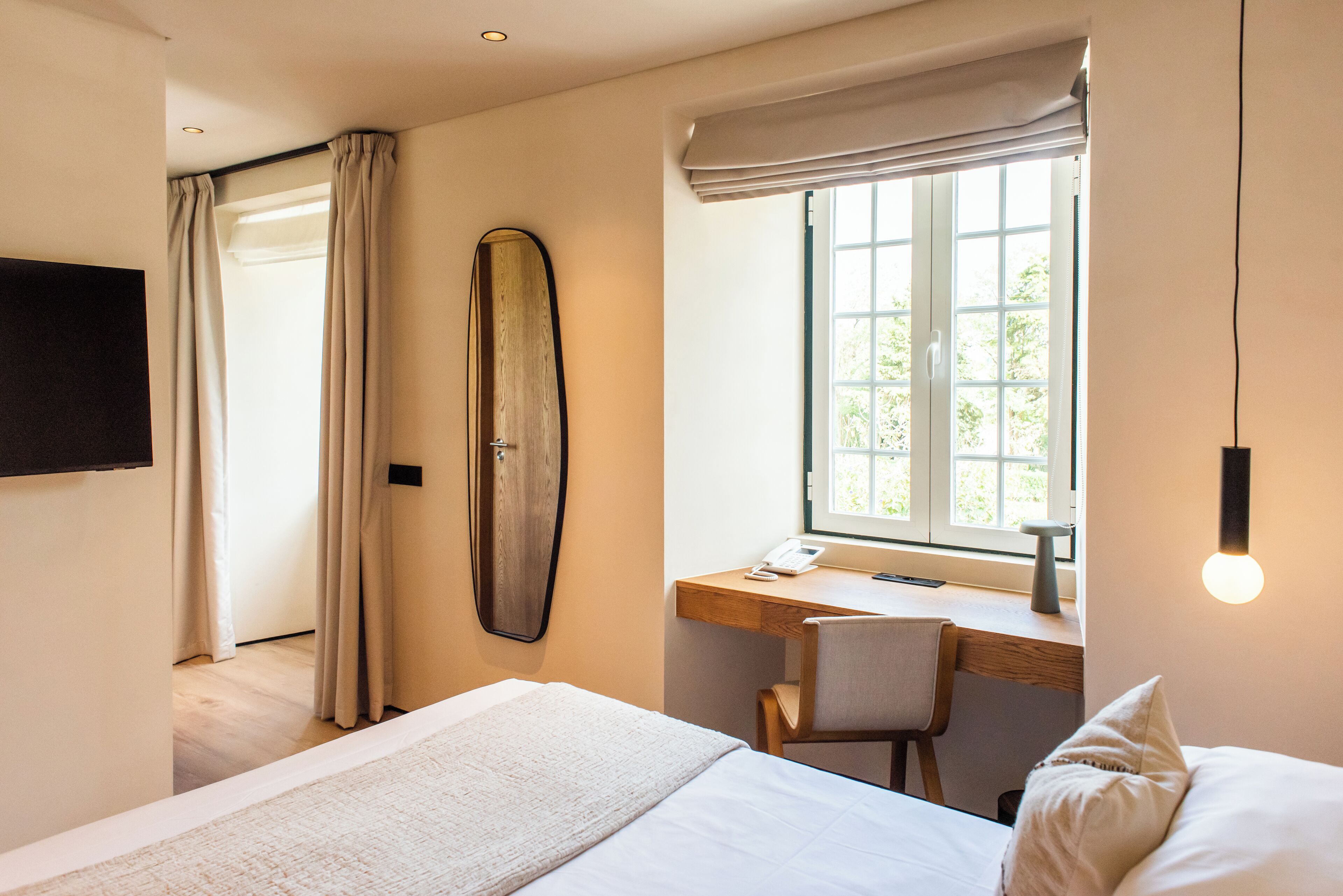 Un dormitorio con cama, escritorio y ventana.