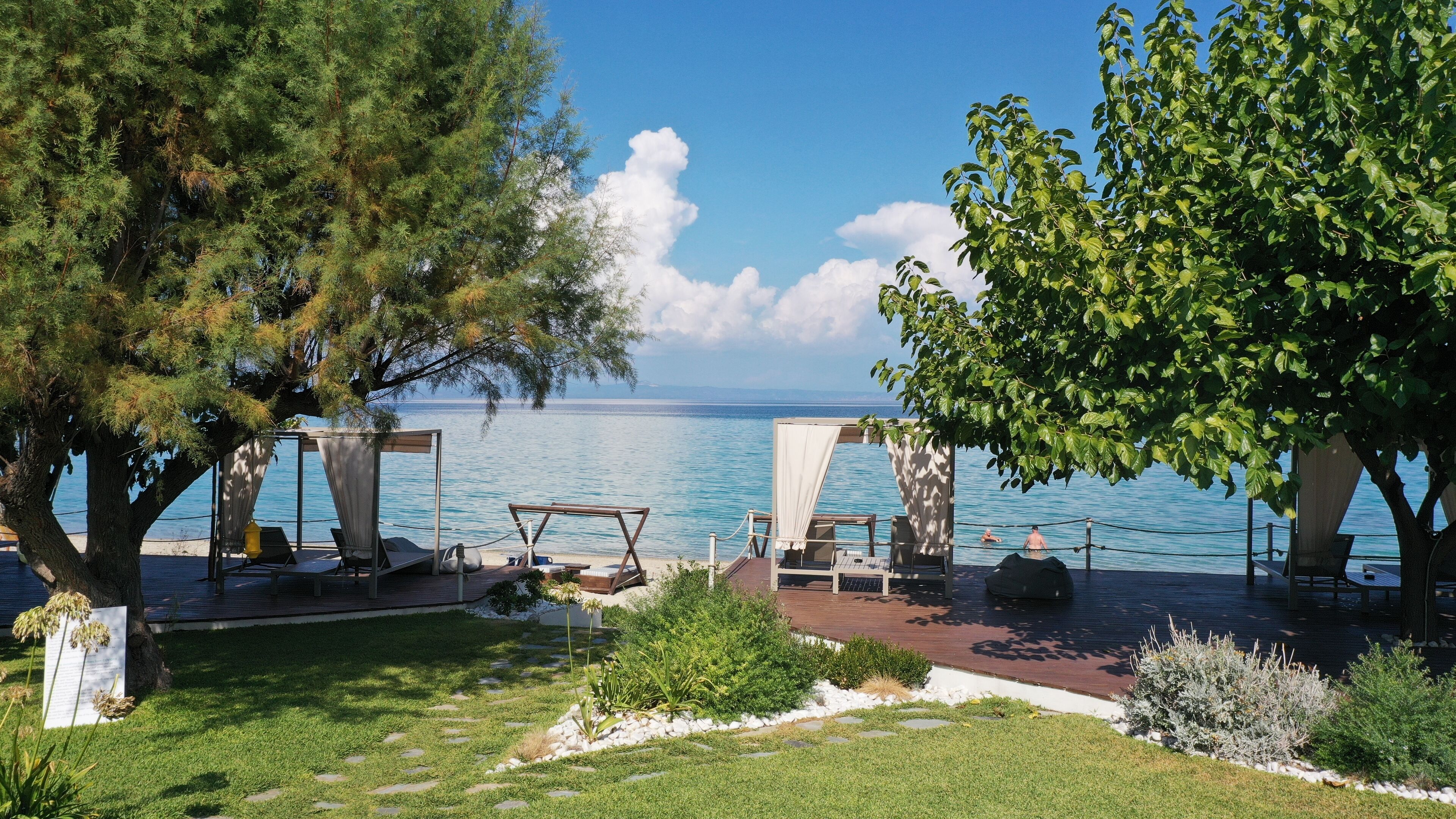 A coastal terrace with outdoor seating, a view of the sea, and a well-maintained garden.