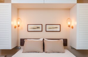 Une chambre à coucher moderne avec un lit, deux lampes fixées au mur et deux tableaux encadrés accrochés au mur.