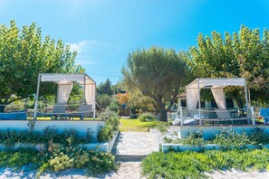 A garden with two covered seating areas, a pathway, and lush greenery. - Villa Despina (Kassandra)