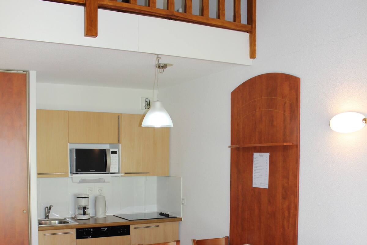 A compact living space with a dining area, kitchenette, and a small seating area with a sofa.