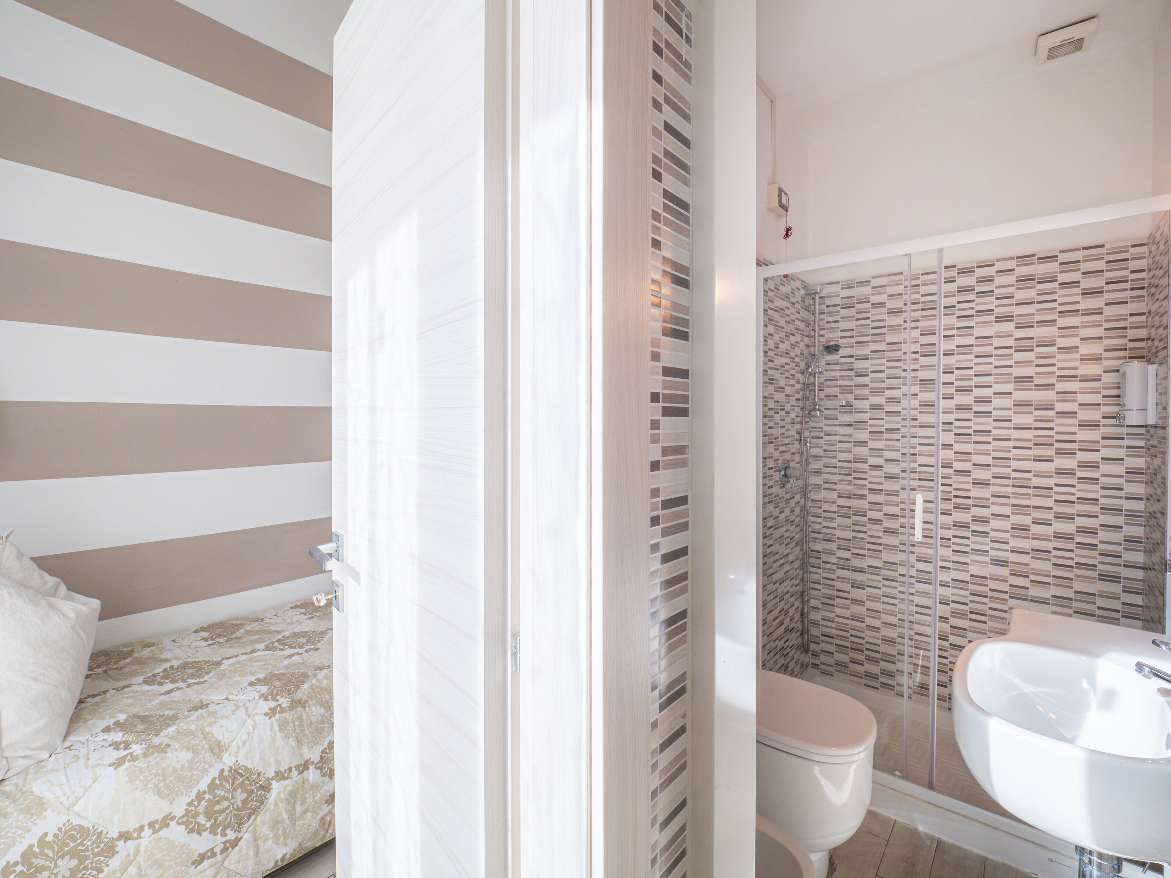 Una camera d'albergo con un letto, un bagno con doccia e lavandino.