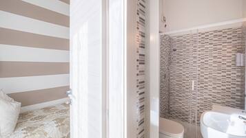 Una camera d'albergo con un letto, un bagno con doccia e lavandino.