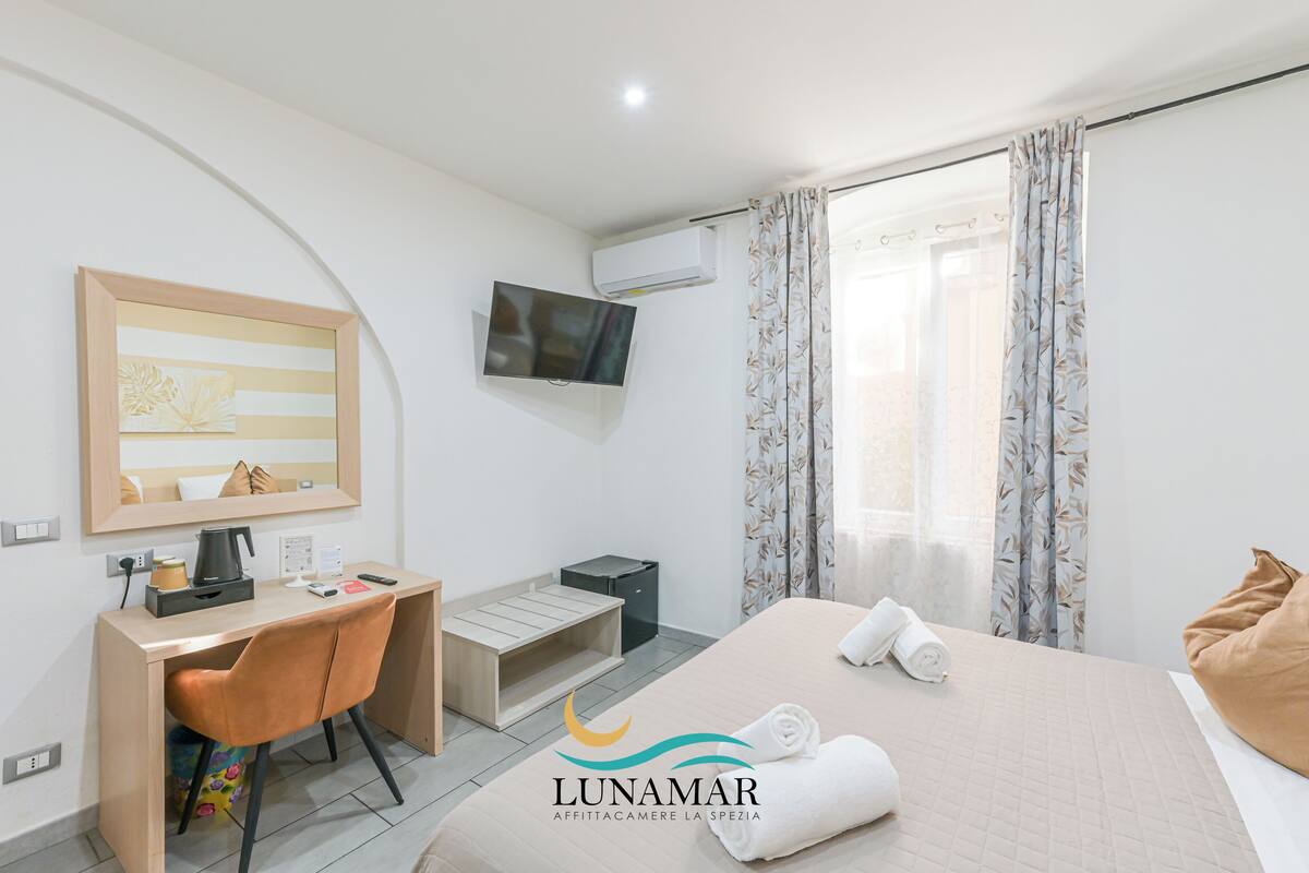 Une chambre d’hôtel équipée d’un lit, d’un bureau, d’une chaise, d’une télévision et d’une fenêtre avec des rideaux.