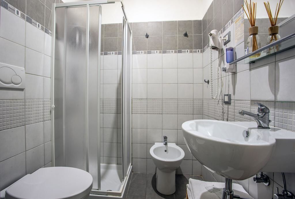 Un bagno moderno con box doccia, un bidet, un water e un lavabo con specchio sopra.