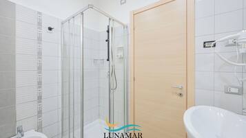 A modern bathroom with a glass-enclosed shower, a wooden door, and a white sink.