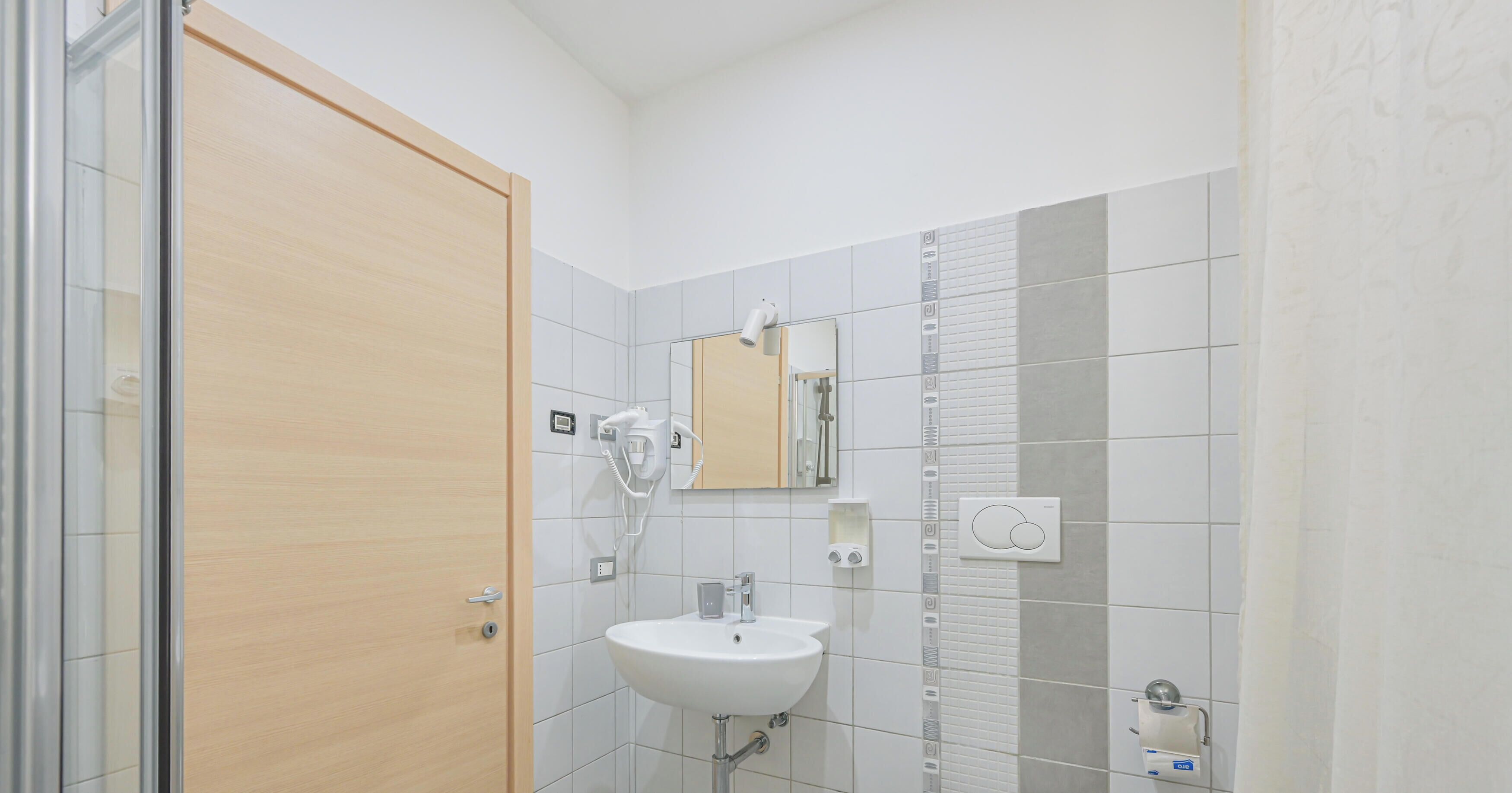 Ein Badezimmer mit Holztür, Waschbecken, Spiegel und Handtuchhalter.