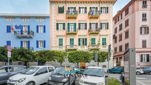 A multi-story building with balconies, parked cars, and a clear sky. - Affittacamere Lunamar (La Spezia)