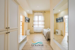 Un dormitorio con cama, televisión, ventana con cortinas y espejo.