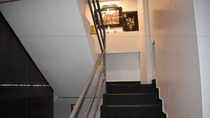 A staircase with a metal railing leading to a landing with framed pictures.