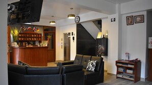 A modern living room with a sofa set, a wooden reception desk, and a staircase.