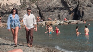 A coastal hotel with a rocky cliff backdrop, a visible restaurant, and a paved walkway leading to the beach. - Hotel Porto Roca (Monterosso al Mare)