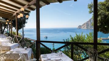 A seaside restaurant with tables set for dining, overlooking the ocean.