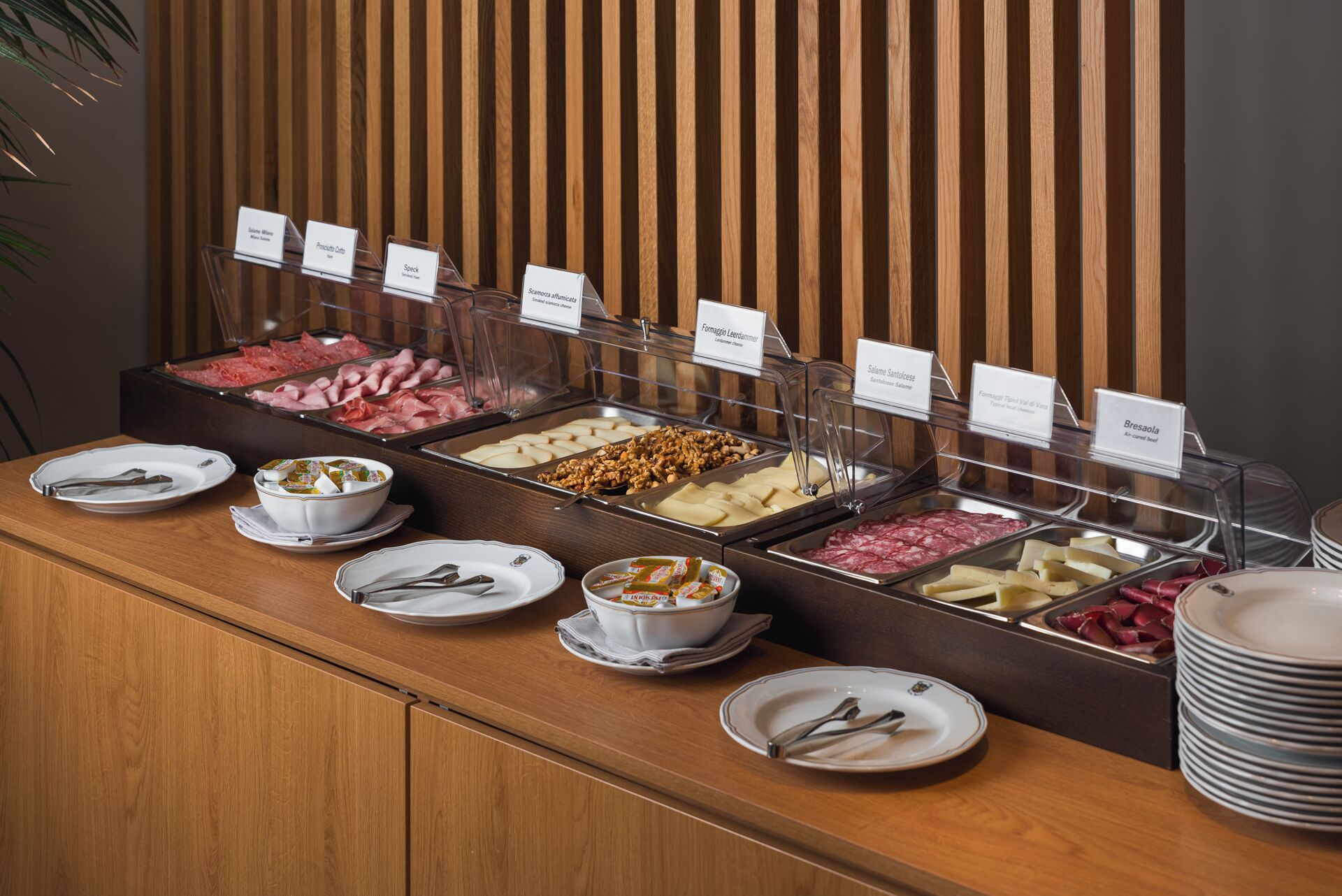 A buffet with various food options, including meats, cheeses, and nuts, with clear labels for each item.