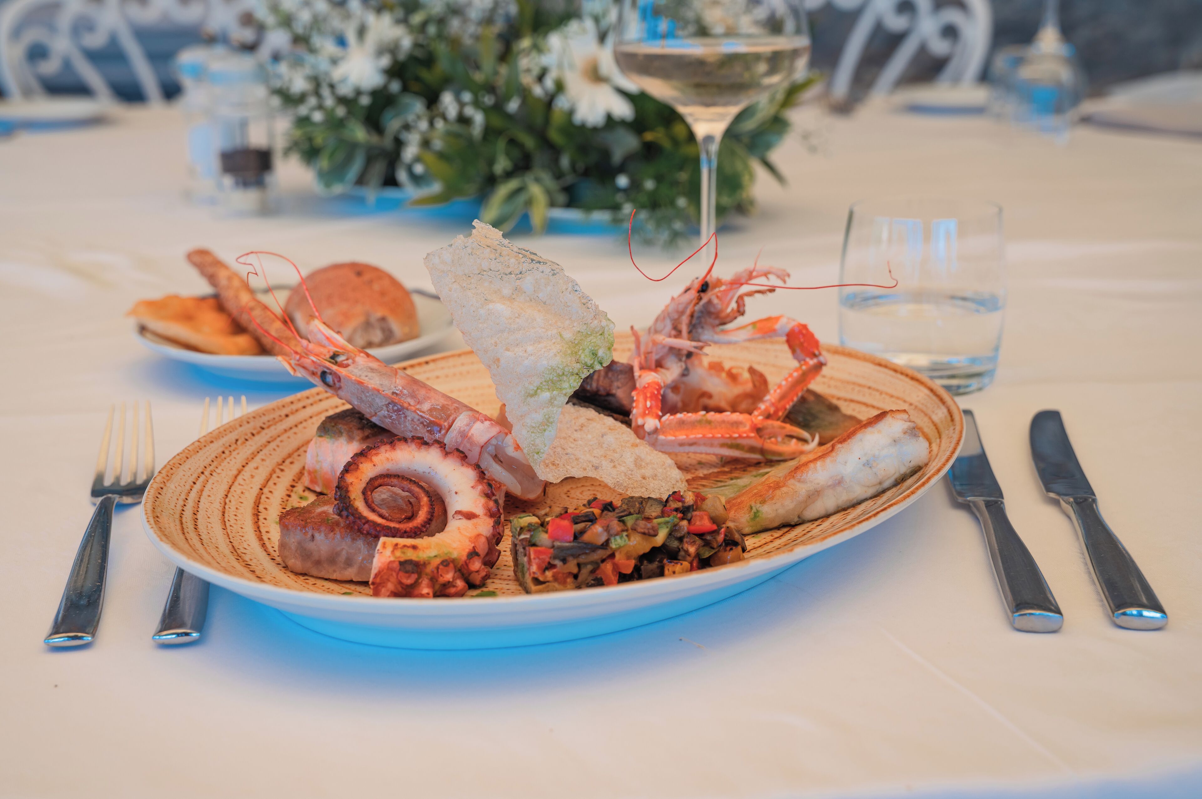 A seafood platter with various grilled items and a glass of water on a table.