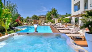 A hot tub and a pool area with lounge chairs and umbrellas. - Tobago Hotel (Garda)
