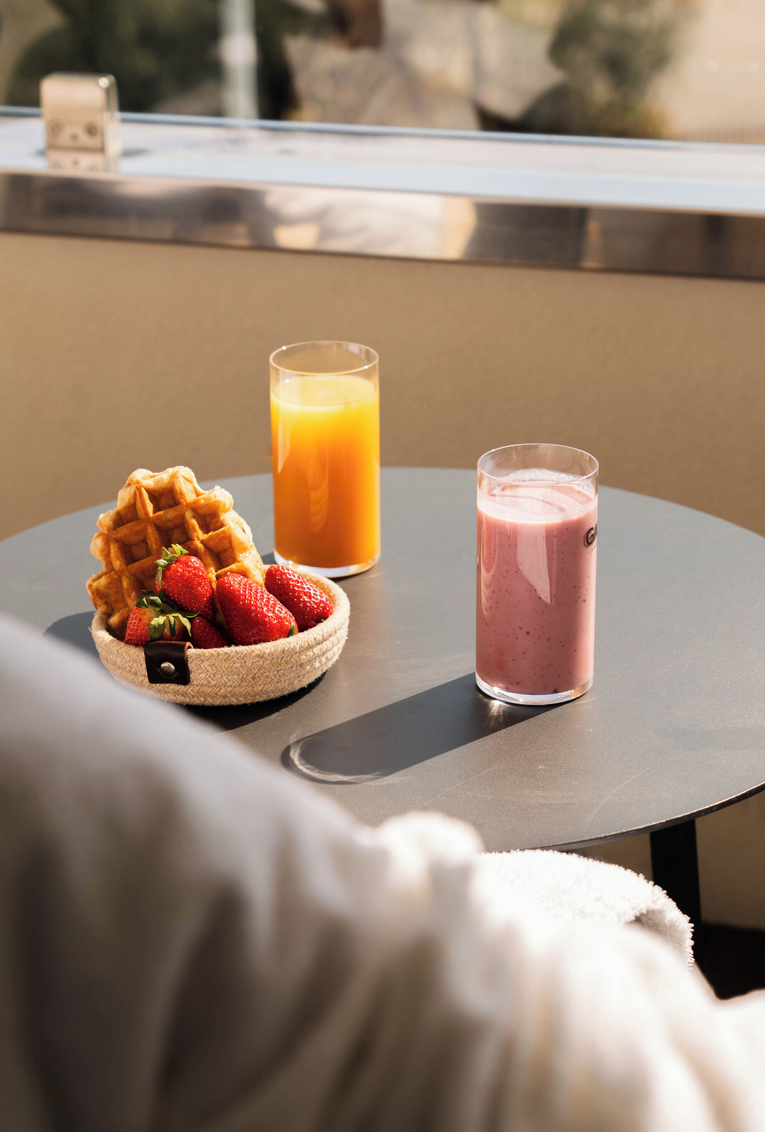 Ein Tisch mit einem Waffel, Erdbeeren und zwei Gläsern Saft.