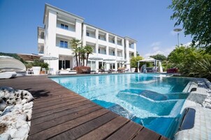 Un hotel moderno con piscina, mobiliario exterior y una terraza de madera.