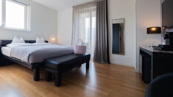 A modern bedroom with a bed, bench, bedside table, and a mirror. - Tobago Hotel (Garda)