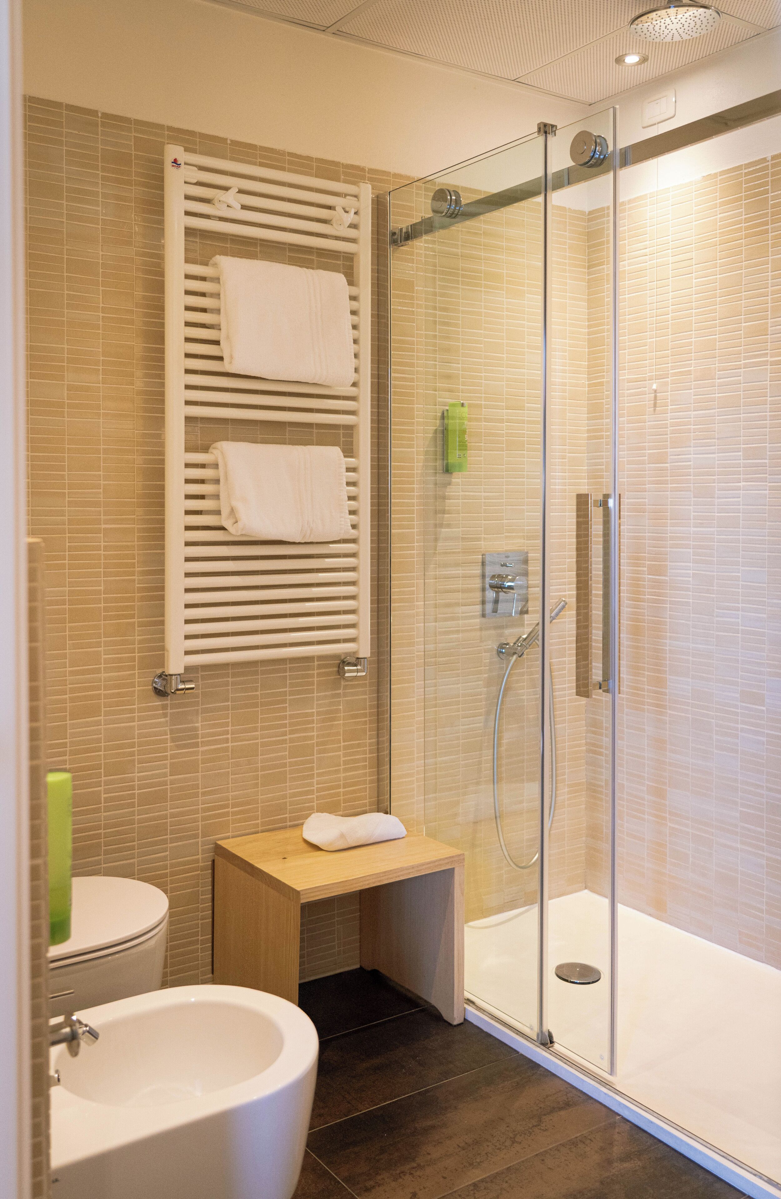 A modern bathroom with a glass-enclosed shower, a white sink, and a small wooden vanity.