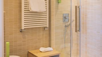 A modern bathroom with a glass-enclosed shower, a white sink, and a small wooden vanity.