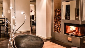 A modern living room with a fireplace, a dining area, and a visible kitchen in the background. - Tobago Hotel (Garda)