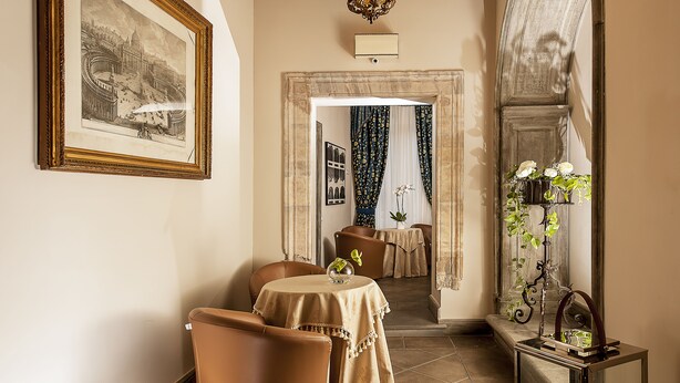 A dining area with a table and chairs, a framed picture on the wall, and a mirror reflecting the room. - Dimora degli Dei (Rome)
