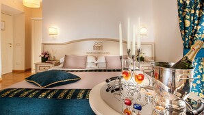 A hotel room with a bed, a bedside table with a lamp, a nightstand with a vase of flowers, and a champagne bottle on the table. - Dimora degli Dei (Rome)
