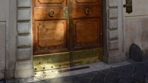 A large wooden double door with a brass threshold, set within an arched stone frame. - Dimora degli Dei (Rome)
