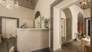 A spacious room with a curved reception desk, a chandelier, and a mirror. - Dimora degli Dei (Rome)