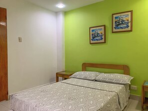 A bedroom with a bed, two nightstands, a wooden door, and two framed pictures on the wall. - Hotel Veleros Cartagena (Cartagena)
