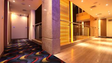 A hotel lobby with a marble column, a patterned carpet, and a glass railing.