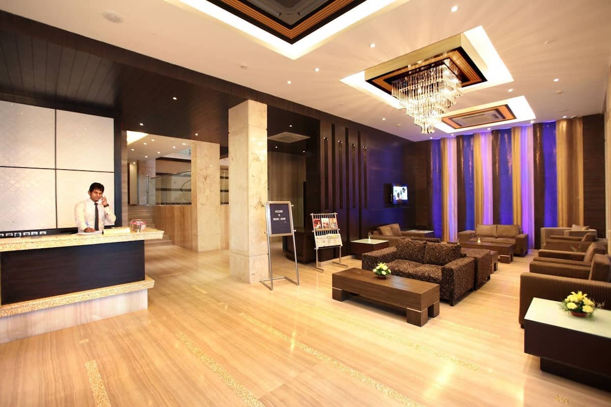 A hotel lobby with a reception desk, seating area, and a chandelier.