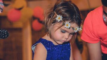 Una persona con camisa roja y un niño con vestido azul y un adorno de flor.