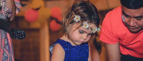 Una persona con camisa roja y un niño con vestido azul y un adorno de flor.