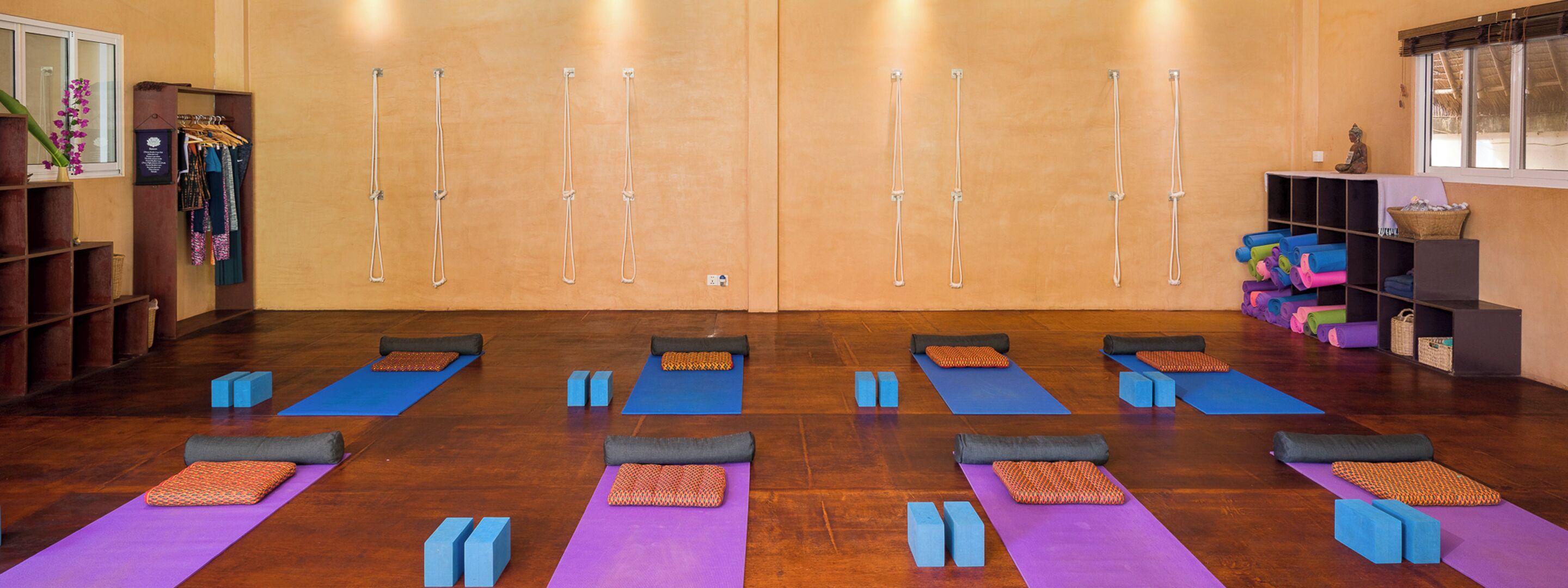 Un studio de yoga équipé de tapis, de briques et doté d’un plancher en bois.